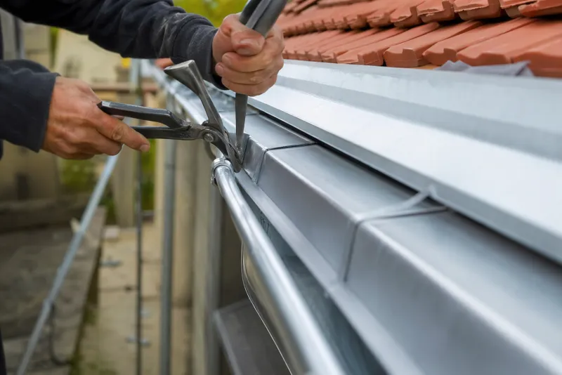 Zingueur Raynier posant une gouttière en zinc sur toiture en tuiles